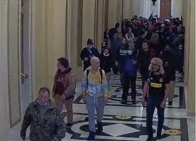 Zachary Jordan Alam, visto en el sombrero de la derecha, fue sentenciado el año pasado a ocho años de prisión por agredir a los oficiales de policía y romper ventanas durante el ataque del Capitolio 2021.